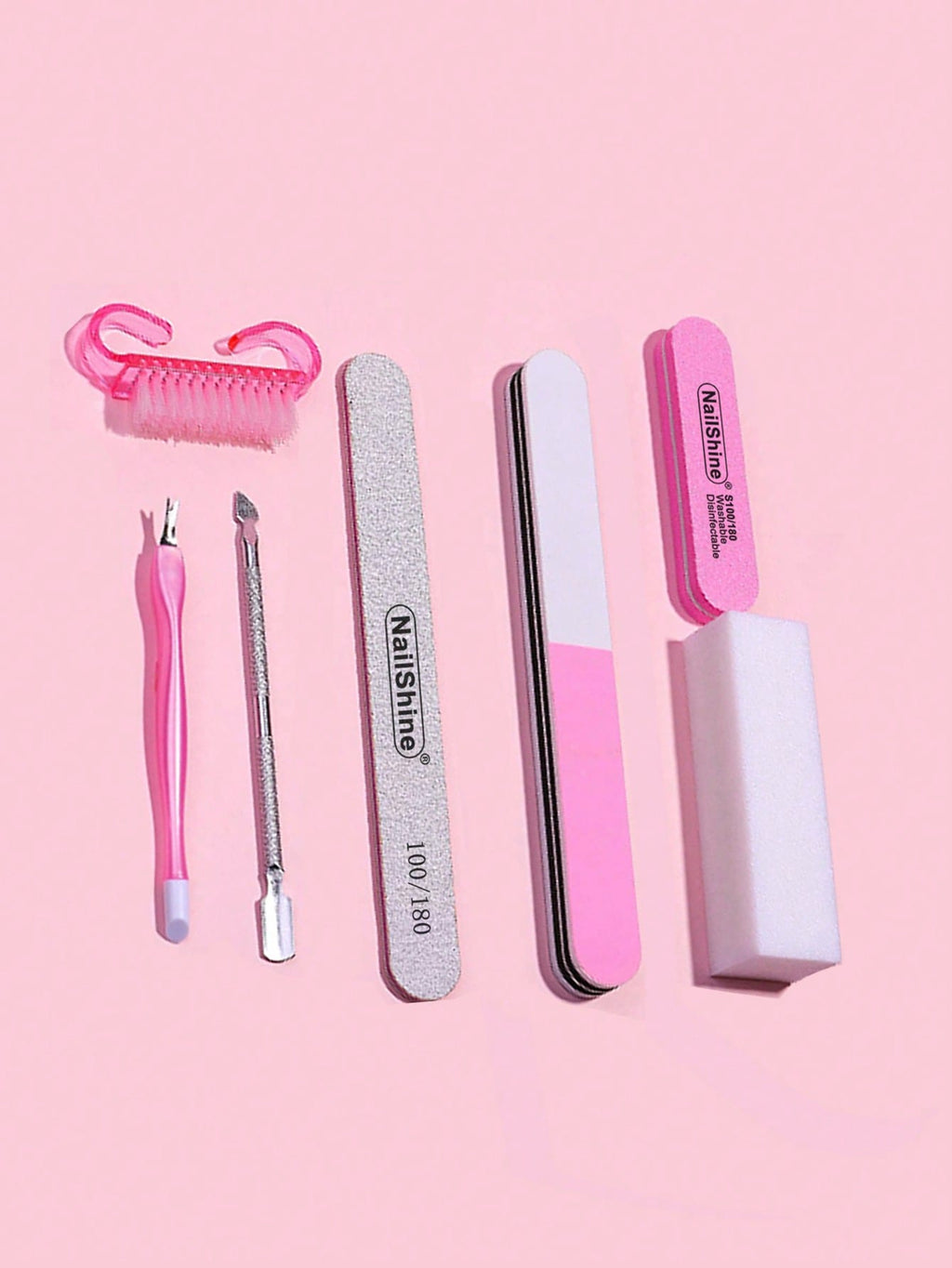 Set of nail care tools including a cuticle nipper, tweezers, and files on a pink background.