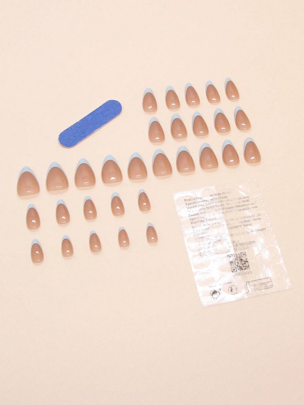 Set of false nails with a nail file and packaging on a beige background