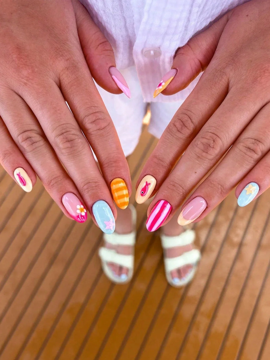 Close-up of hands with colorful nail designs on a wooden surface