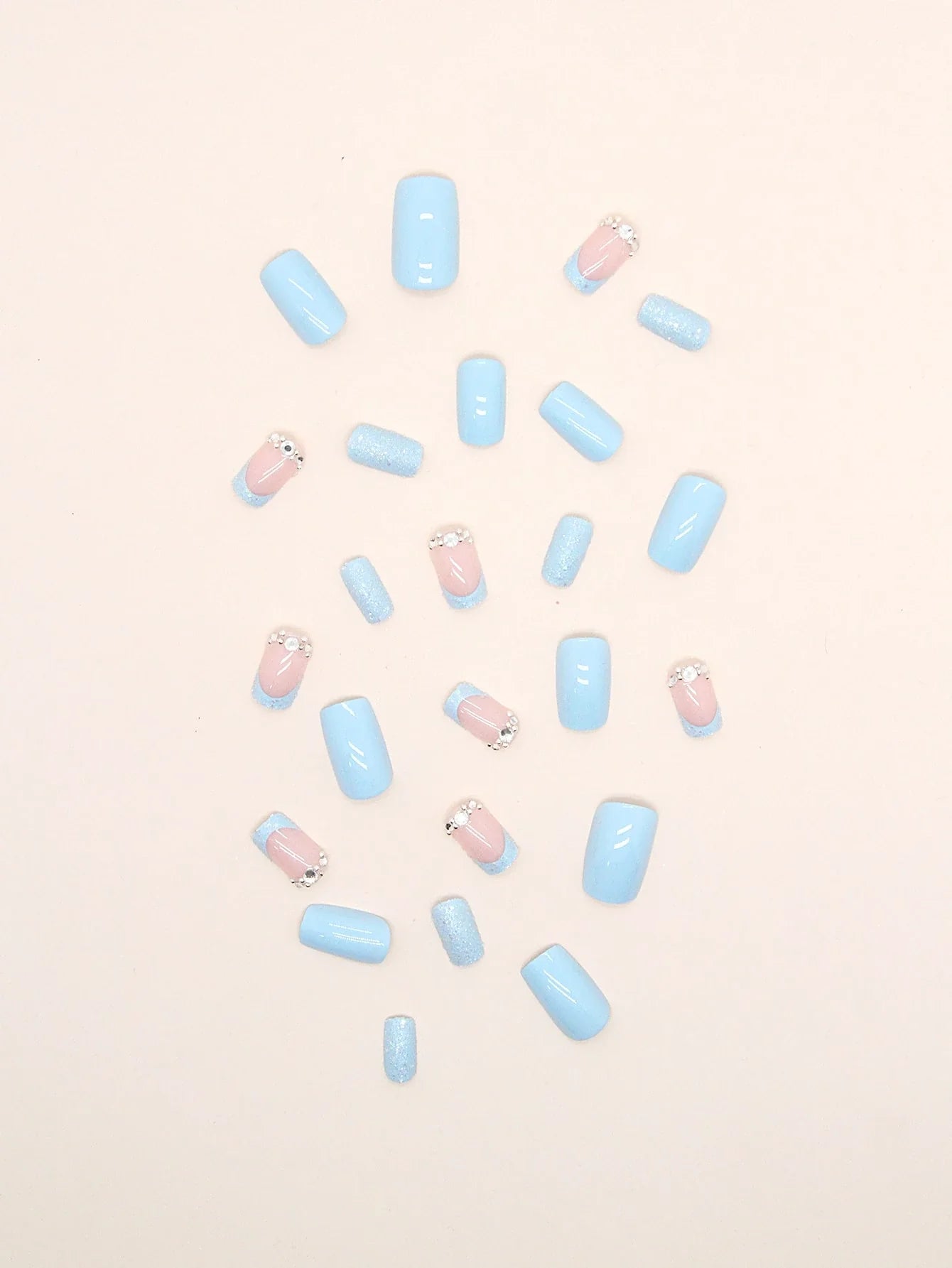 Pastel blue and pink nail polish bottles scattered on a light pink background