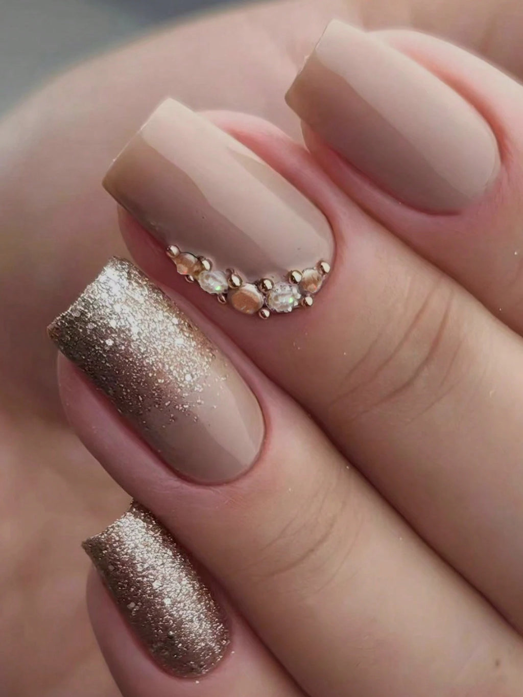 Close-up of a hand with beige and rose gold nail polish