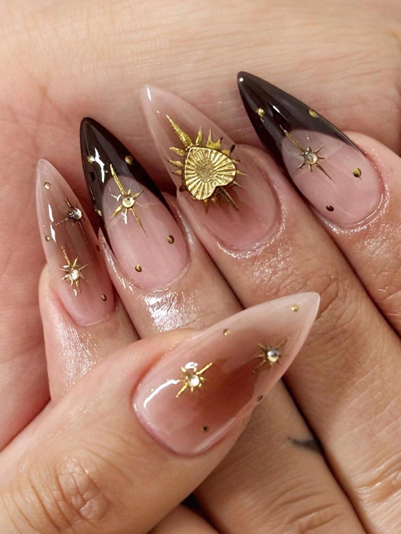 Nails with gold star and sun designs on a light background