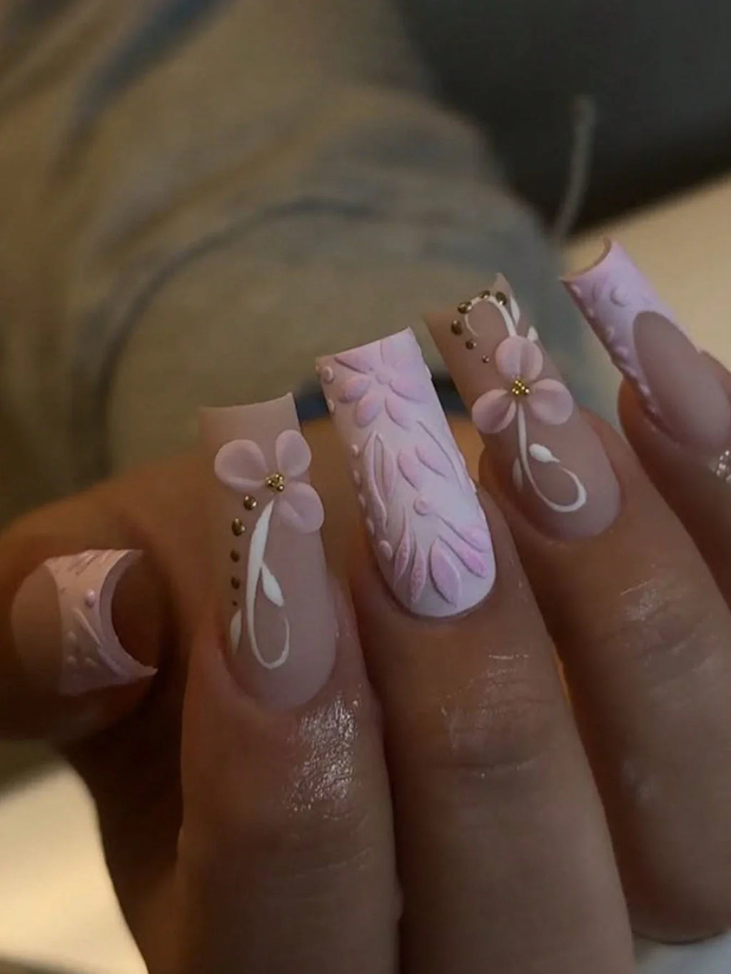 Close-up of a hand with pink floral and leaf nail art.
