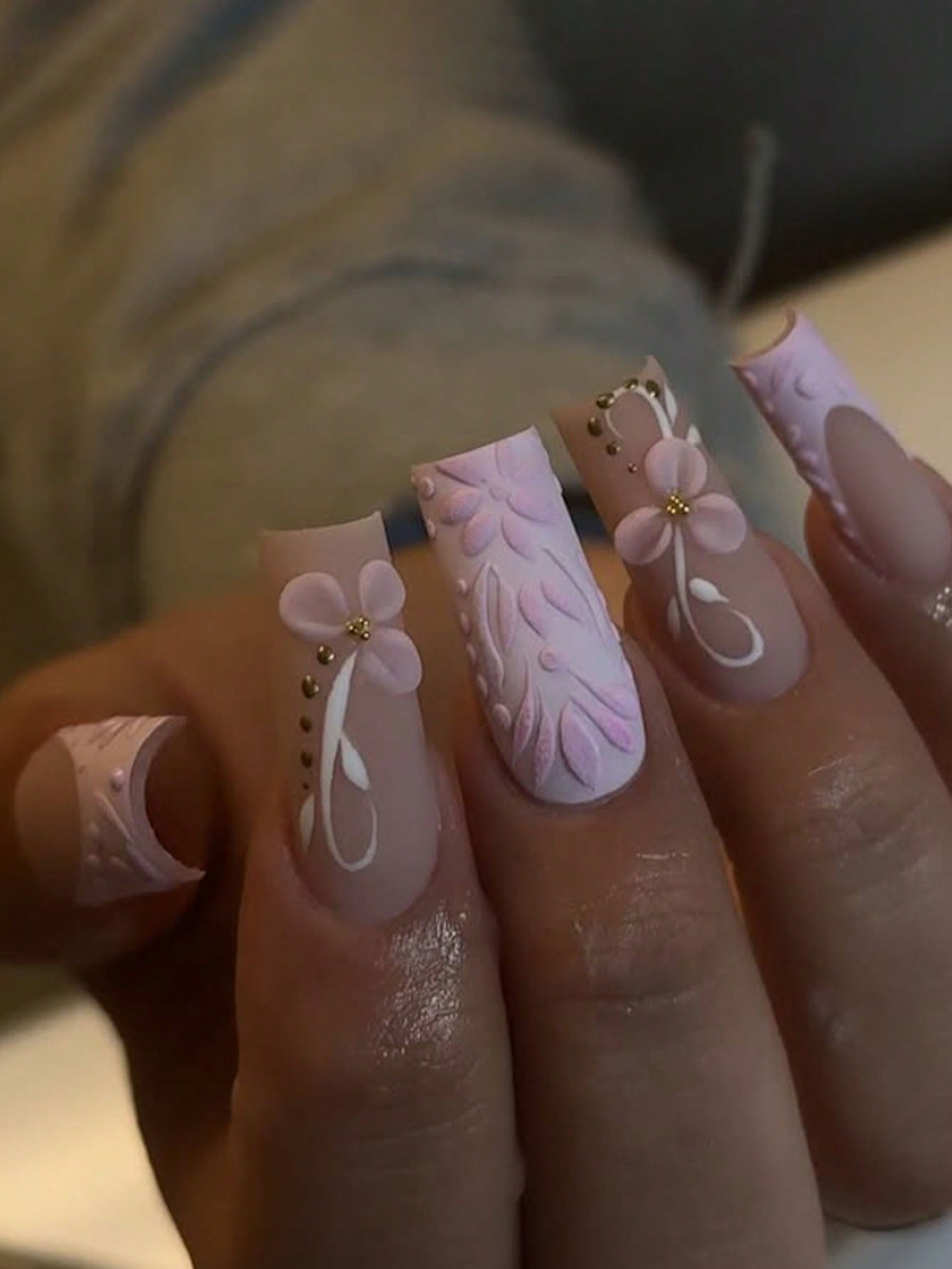 Close-up of a hand with pink floral and leaf nail art.