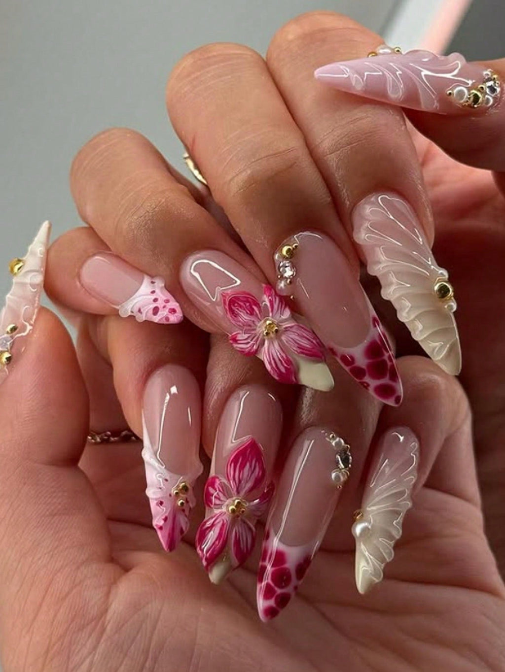 Close-up of hands with decorative nails featuring flowers and butterflies.