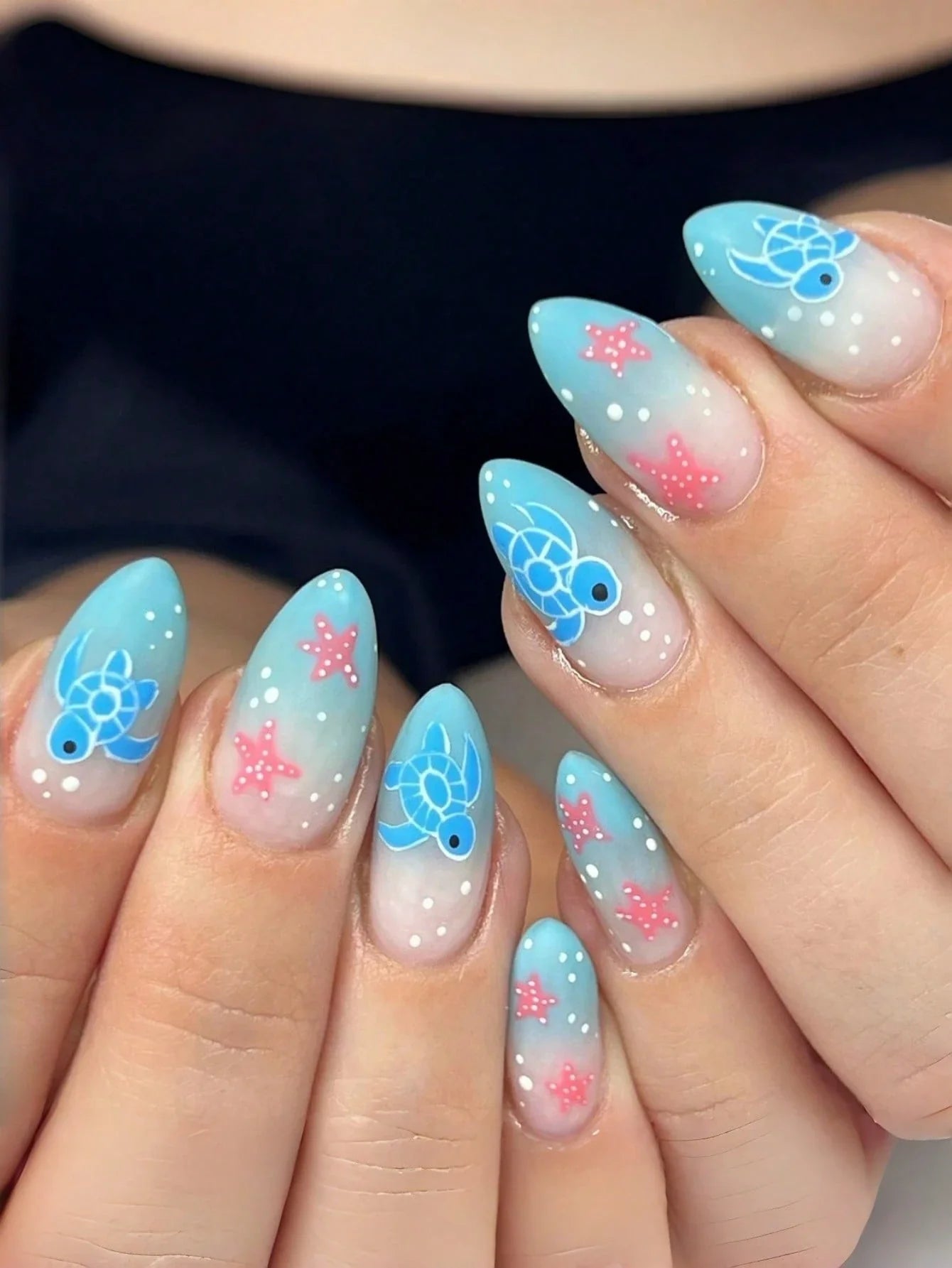 Nails with turtle and starfish designs in blue and pink on a light background
