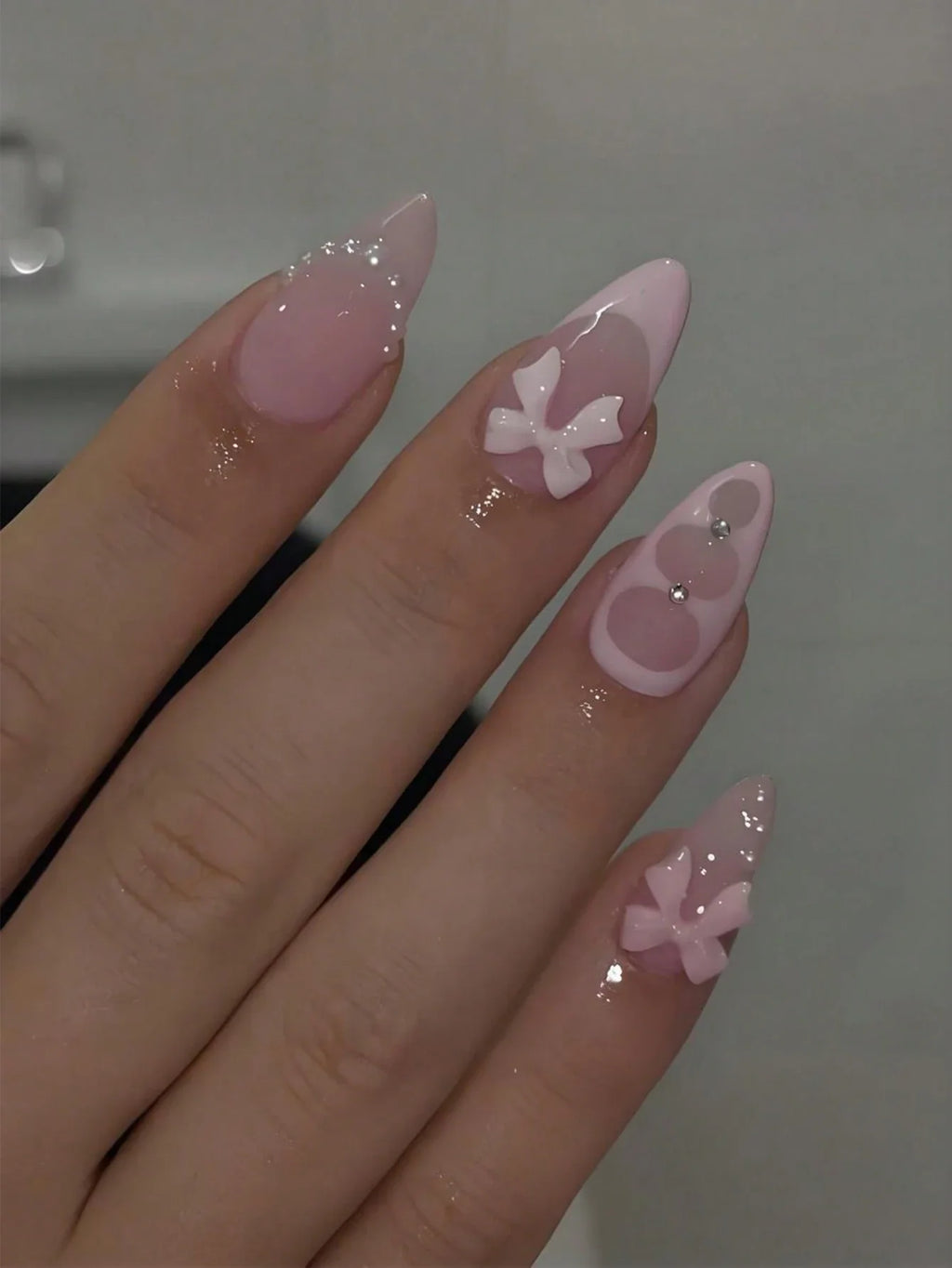 Hand with pink nail art featuring butterfly designs on a neutral background