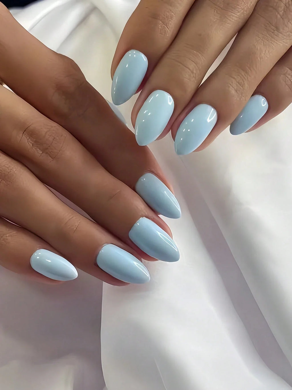 Close-up of hands with light blue nail polish on a white background