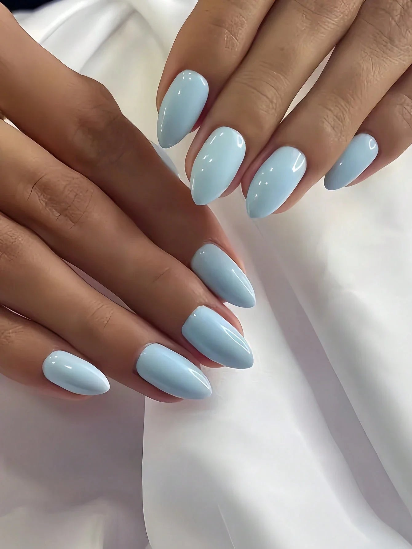 Close-up of hands with light blue nail polish on a white background