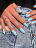 Close-up of hands with light blue nail polish on a denim background