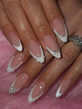 Nails with decorative bow and rhinestone design on a pink background