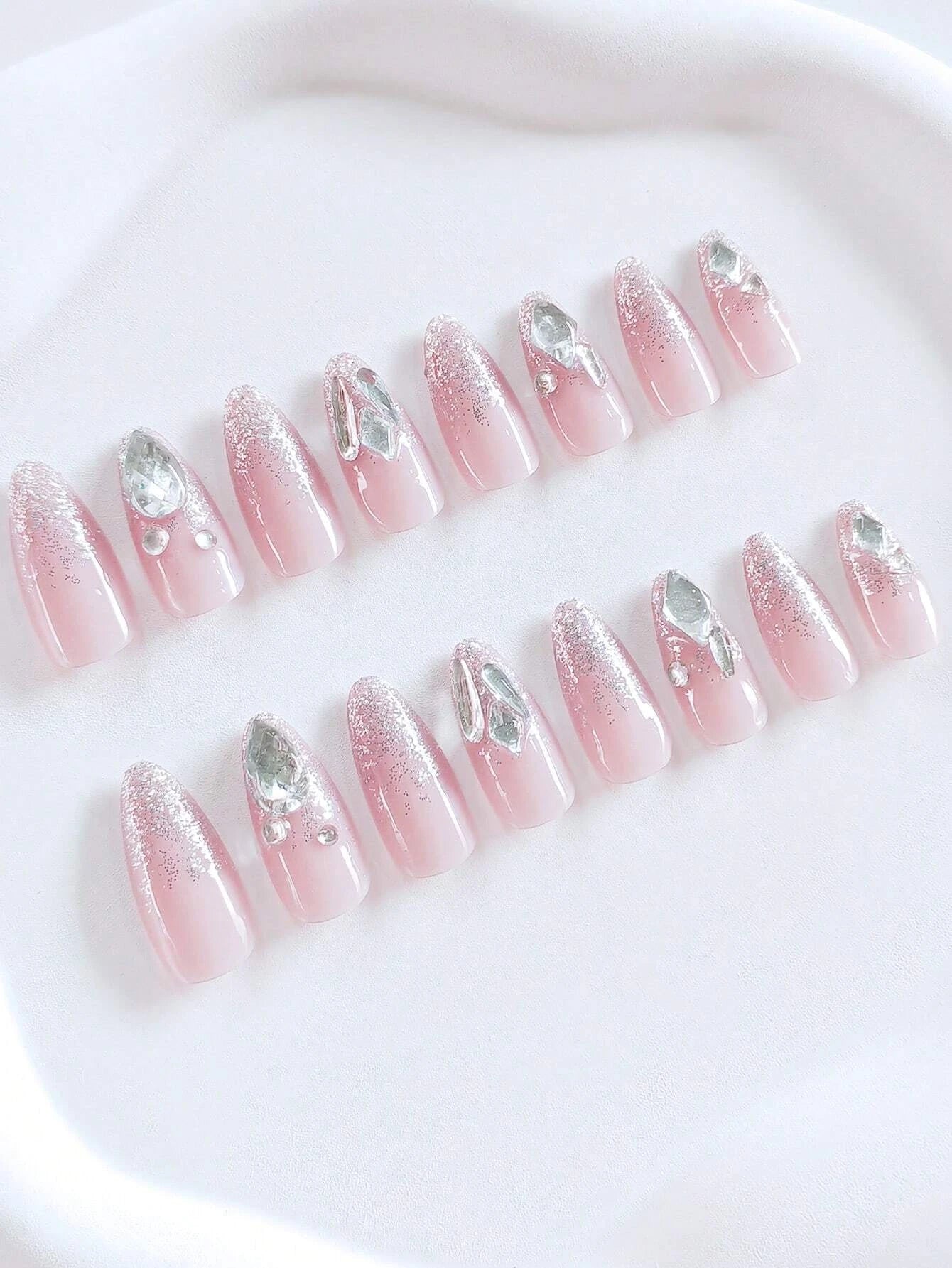 Set of pink press-on nails with silver rhinestones on a white background