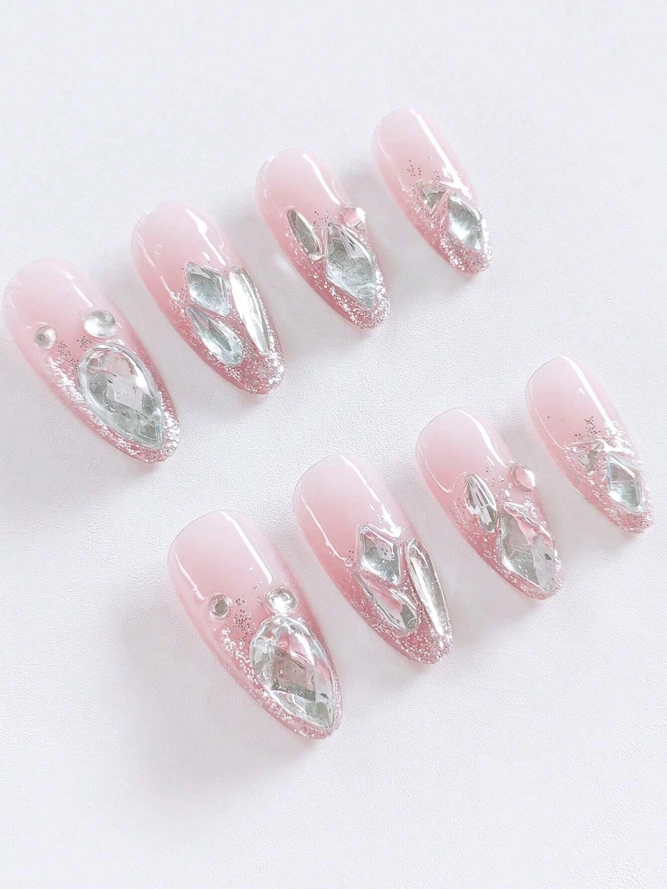 Set of pink press-on nails with silver rhinestones on a white background